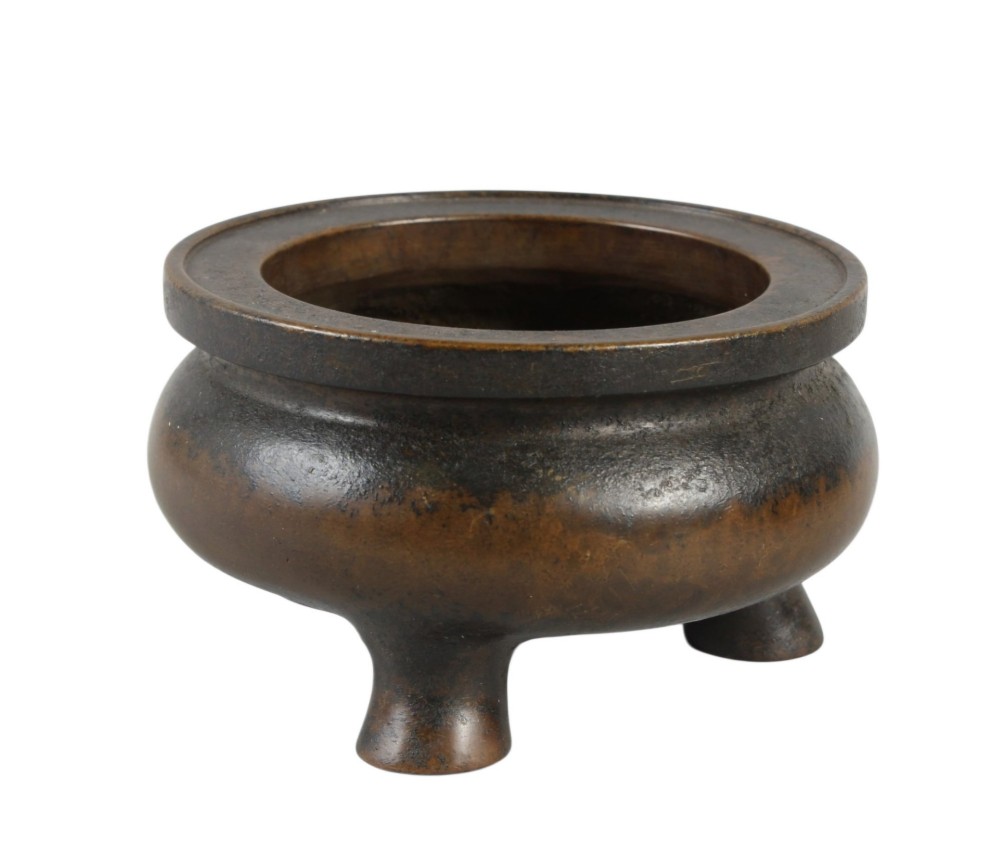 A heavy 17th-century Chinese archaistic bronze tripod censer featuring a compressed globular body, wide flat rim, dark brown patina, and three sturdy feet. View V