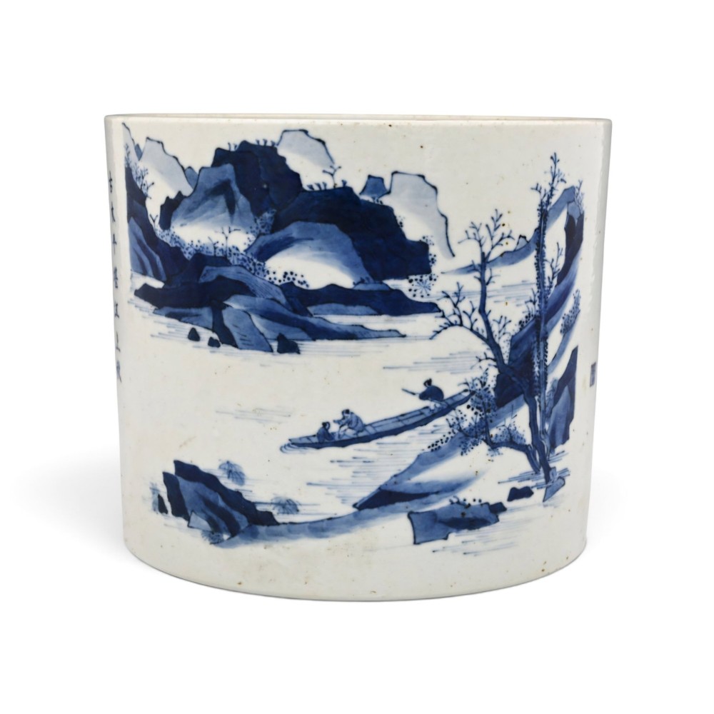A cylindrical Chinese blue and white porcelain brush pot decorated with a painted mountain landscape and calligraphic text. View II