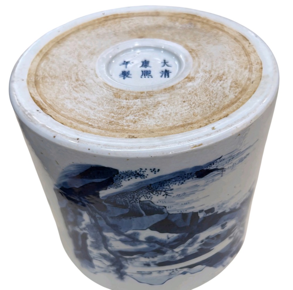 A cylindrical Chinese blue and white porcelain brush pot decorated with a painted mountain landscape and calligraphic text. View X