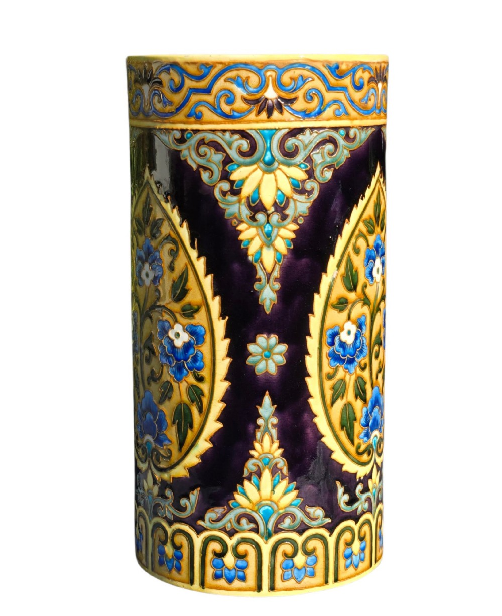 A tall cylindrical ceramic umbrella stand decorated with colourful Iznik-style floral medallions, turquoise scrolling foliage, and a deep purple glazed background. View V