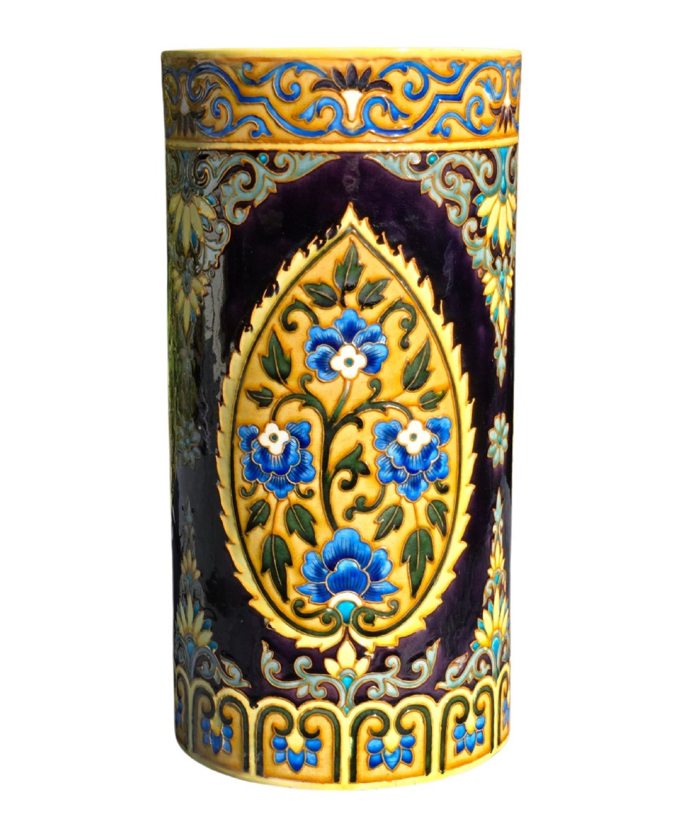 A tall cylindrical ceramic umbrella stand decorated with colourful Iznik-style floral medallions, turquoise scrolling foliage, and a deep purple glazed background. View VI