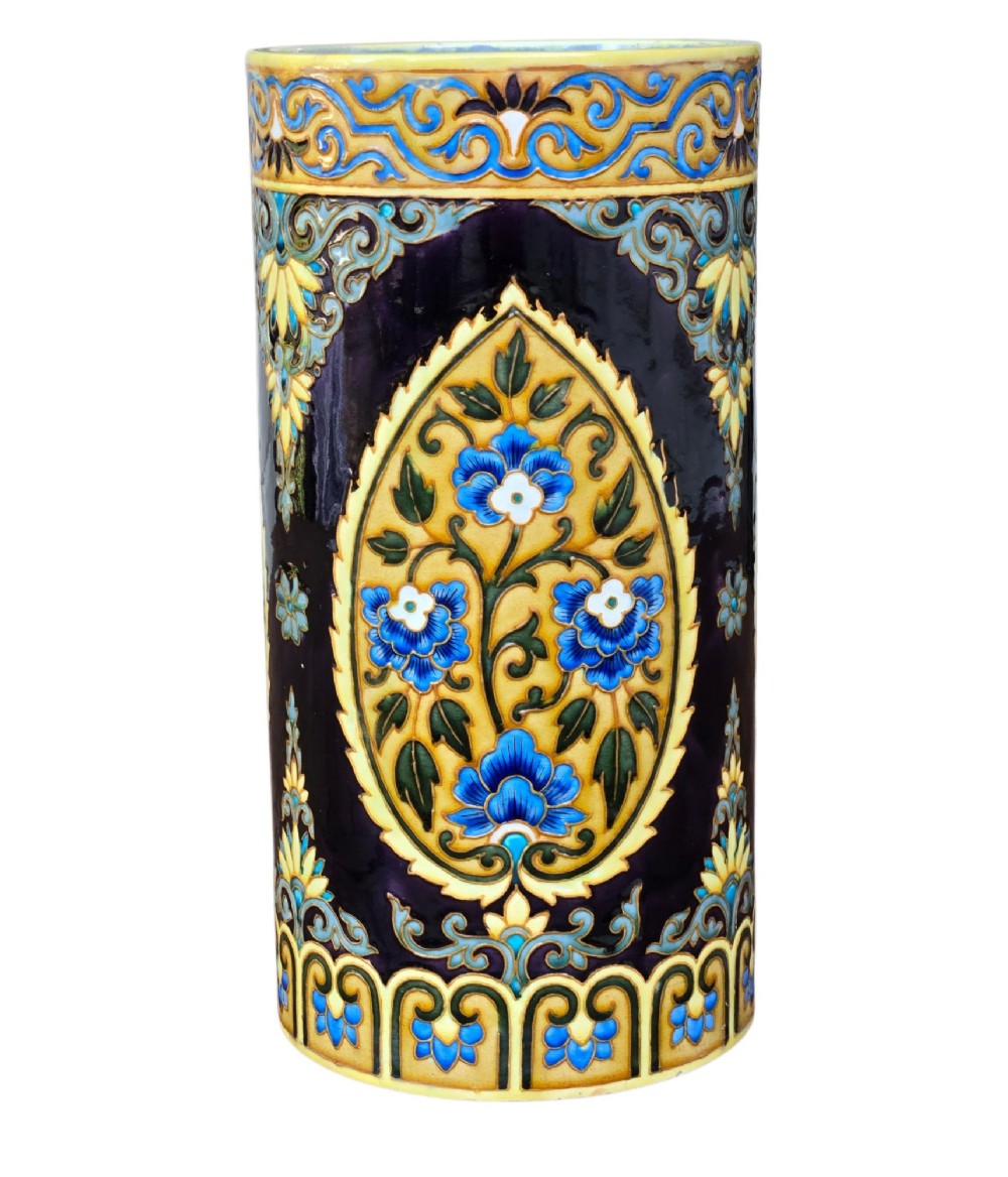 A tall cylindrical ceramic umbrella stand decorated with colourful Iznik-style floral medallions, turquoise scrolling foliage, and a deep purple glazed background. View IX
