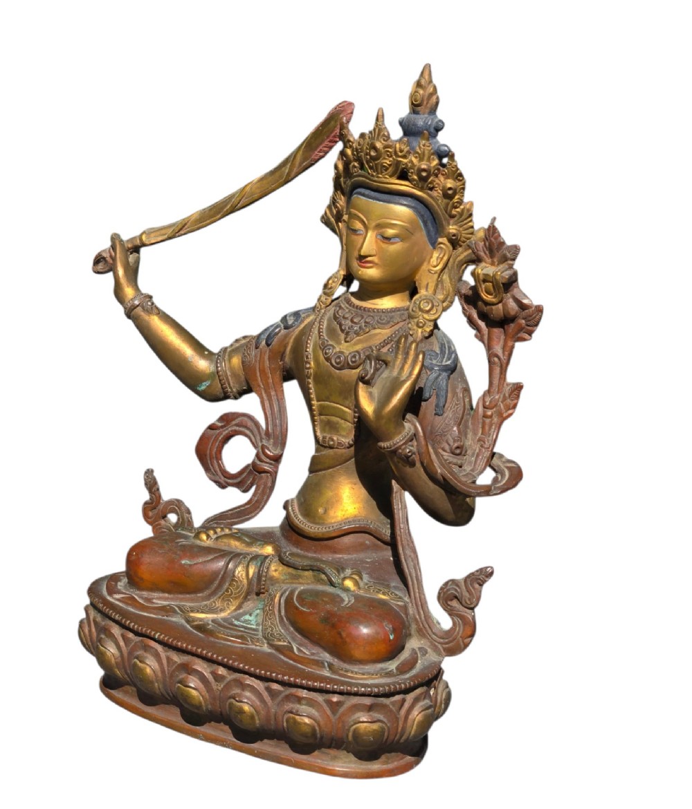An antique Sino-Tibetan gilt-bronze figure of Bodhisattva Manjushri seated cross-legged on a double-lotus base, brandishing a flaming sword in his right hand. View V