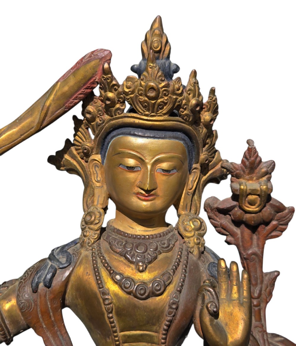 An antique Sino-Tibetan gilt-bronze figure of Bodhisattva Manjushri seated cross-legged on a double-lotus base, brandishing a flaming sword in his right hand. View XII