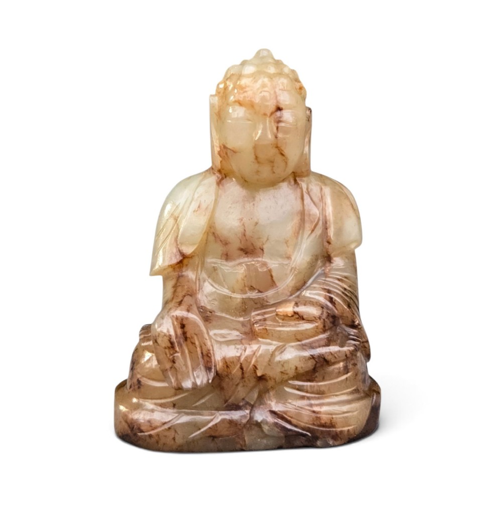 A carved celadon and brown jade sculpture depicting a seated Buddha figure in traditional robes. View X