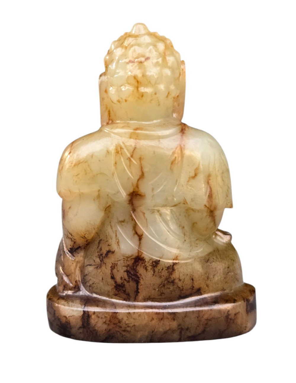 A carved celadon and brown jade sculpture depicting a seated Buddha figure in traditional robes. View XI
