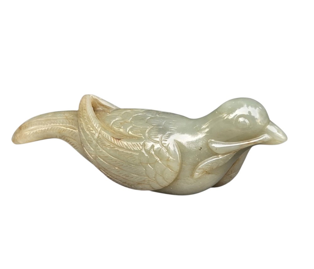 A carved celadon jade figure depicting a resting water bird holding a leafy stem in its beak. View II