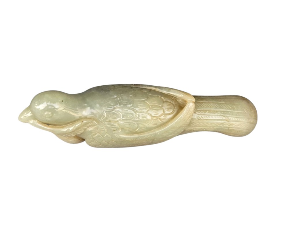 A carved celadon jade figure depicting a resting water bird holding a leafy stem in its beak. View III
