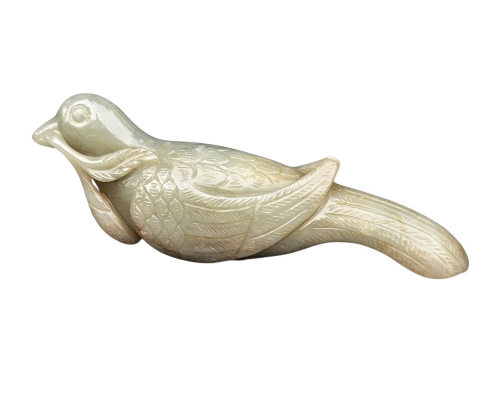 A carved celadon jade figure depicting a resting water bird holding a leafy stem in its beak. View IV