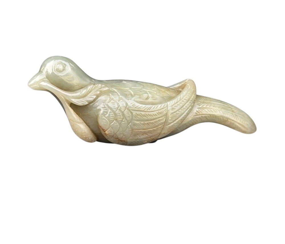 A carved celadon jade figure depicting a resting water bird holding a leafy stem in its beak. View V