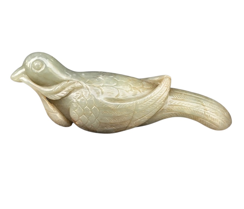 A carved celadon jade figure depicting a resting water bird holding a leafy stem in its beak. View VI