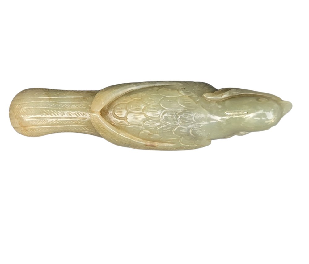 A carved celadon jade figure depicting a resting water bird holding a leafy stem in its beak. View VII