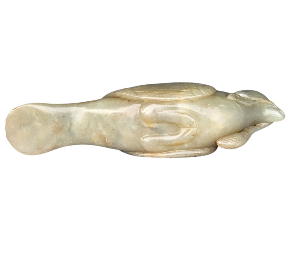 A carved celadon jade figure depicting a resting water bird holding a leafy stem in its beak. View VIII