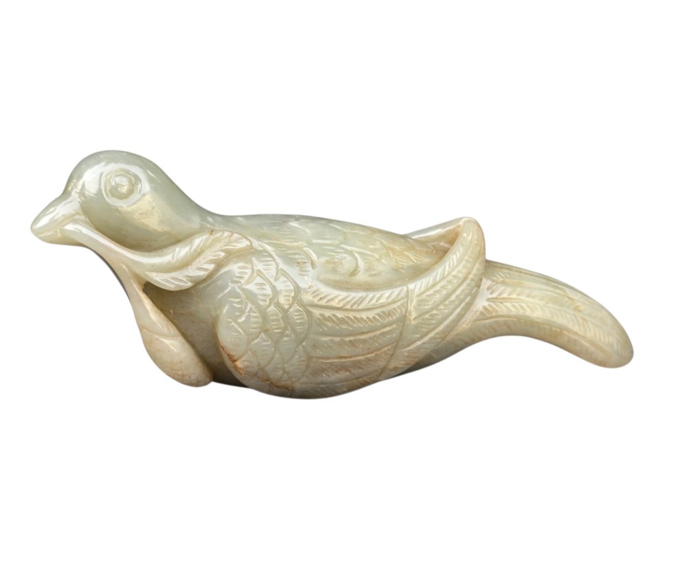 A carved celadon jade figure depicting a resting water bird holding a leafy stem in its beak. View IX