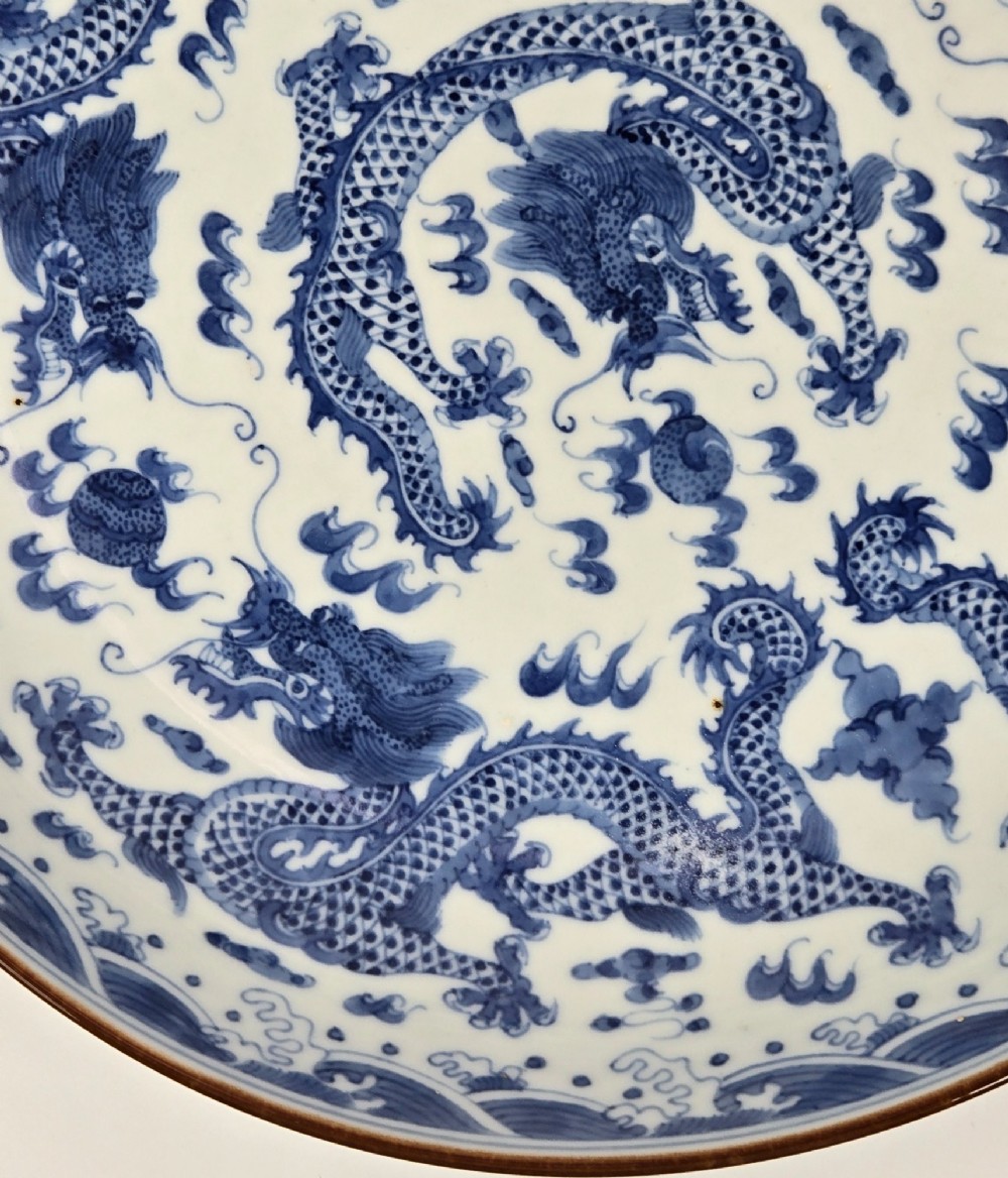 A circular Chinese blue and white porcelain charger featuring five-clawed dragons depicted among stylized clouds and flaming pearls. View V