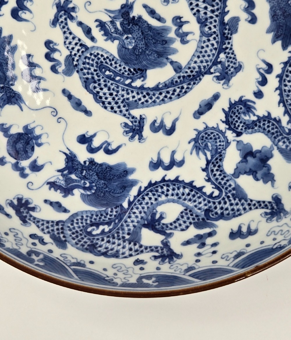 A circular Chinese blue and white porcelain charger featuring five-clawed dragons depicted among stylized clouds and flaming pearls. View VII