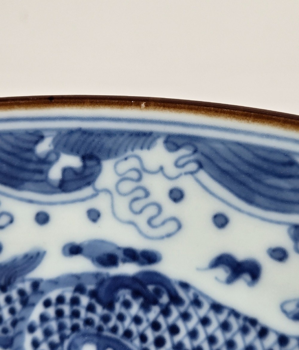 A circular Chinese blue and white porcelain charger featuring five-clawed dragons depicted among stylized clouds and flaming pearls. View XI