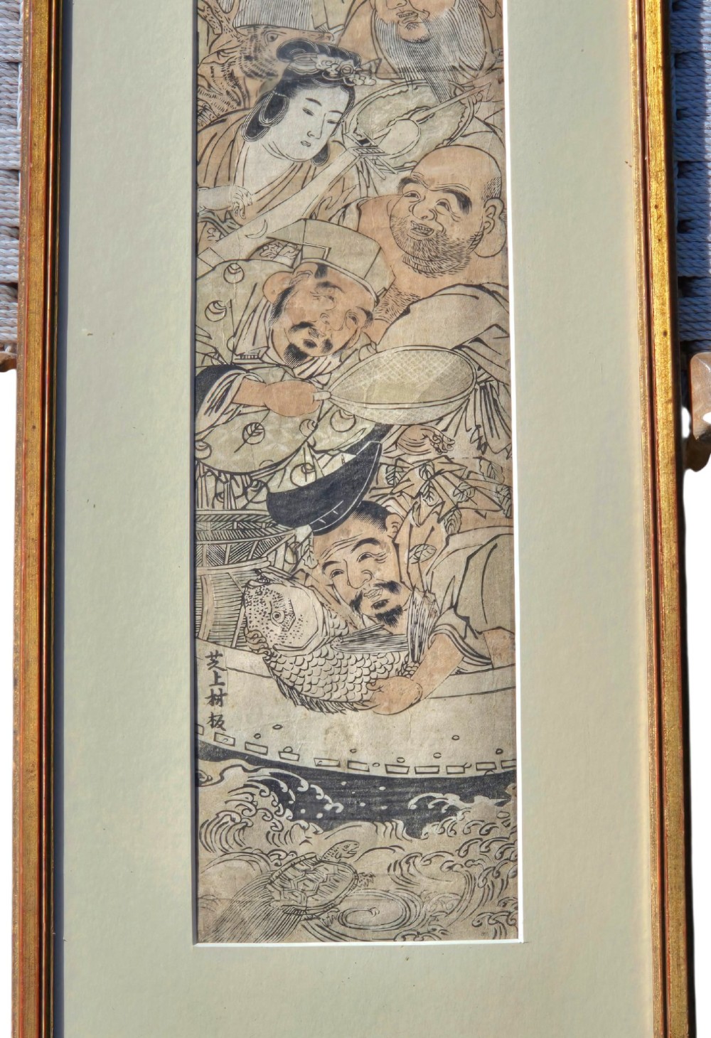 A tall framed Japanese ukiyo-e woodblock print depicting seven figures aboard a vessel beneath a flying crane, presented in a gold frame with a wide cream mount. View X