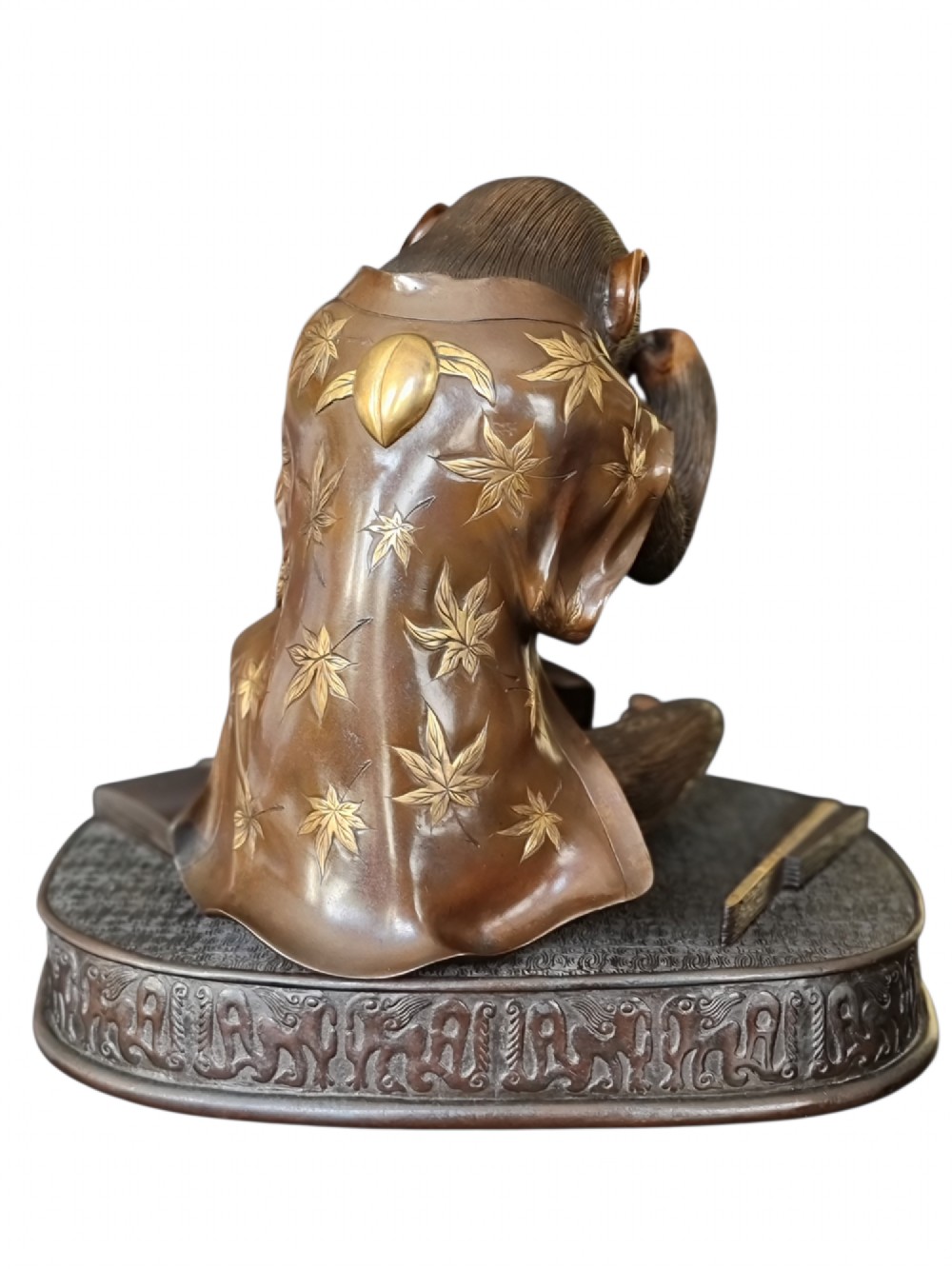 A dark bronze Japanese okimono sculpture depicting an anthropomorphic monkey wearing spectacles, seated with a book and inro. View VIII