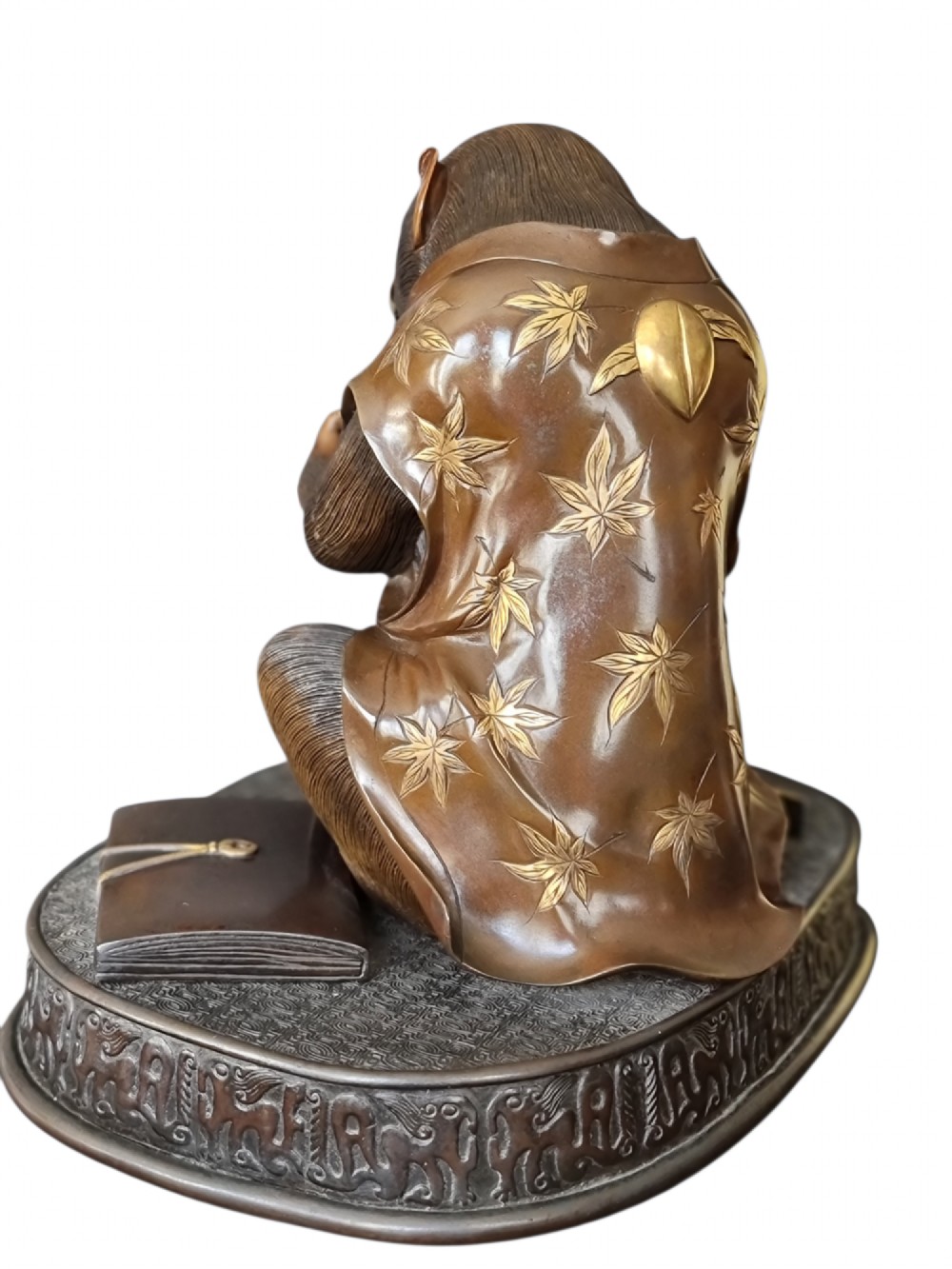 A dark bronze Japanese okimono sculpture depicting an anthropomorphic monkey wearing spectacles, seated with a book and inro. View IX