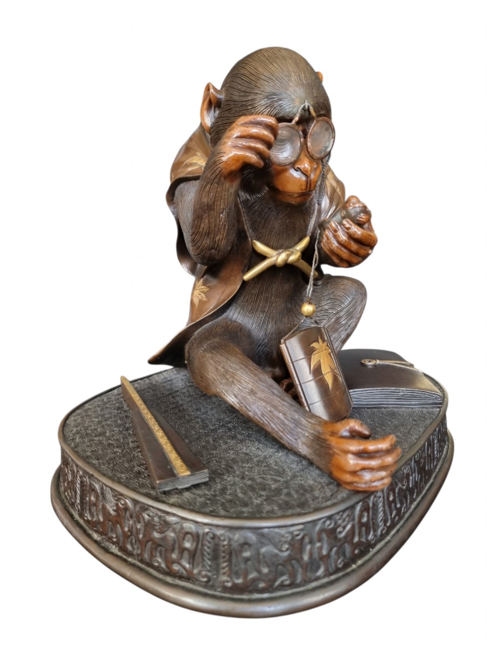 A dark bronze Japanese okimono sculpture depicting an anthropomorphic monkey wearing spectacles, seated with a book and inro. View XI