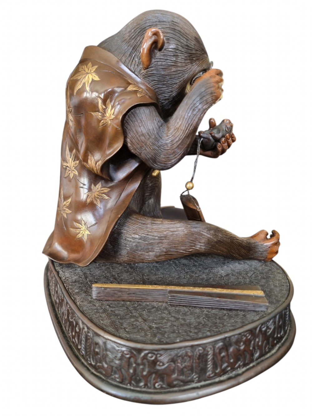A dark bronze Japanese okimono sculpture depicting an anthropomorphic monkey wearing spectacles, seated with a book and inro. View XIV