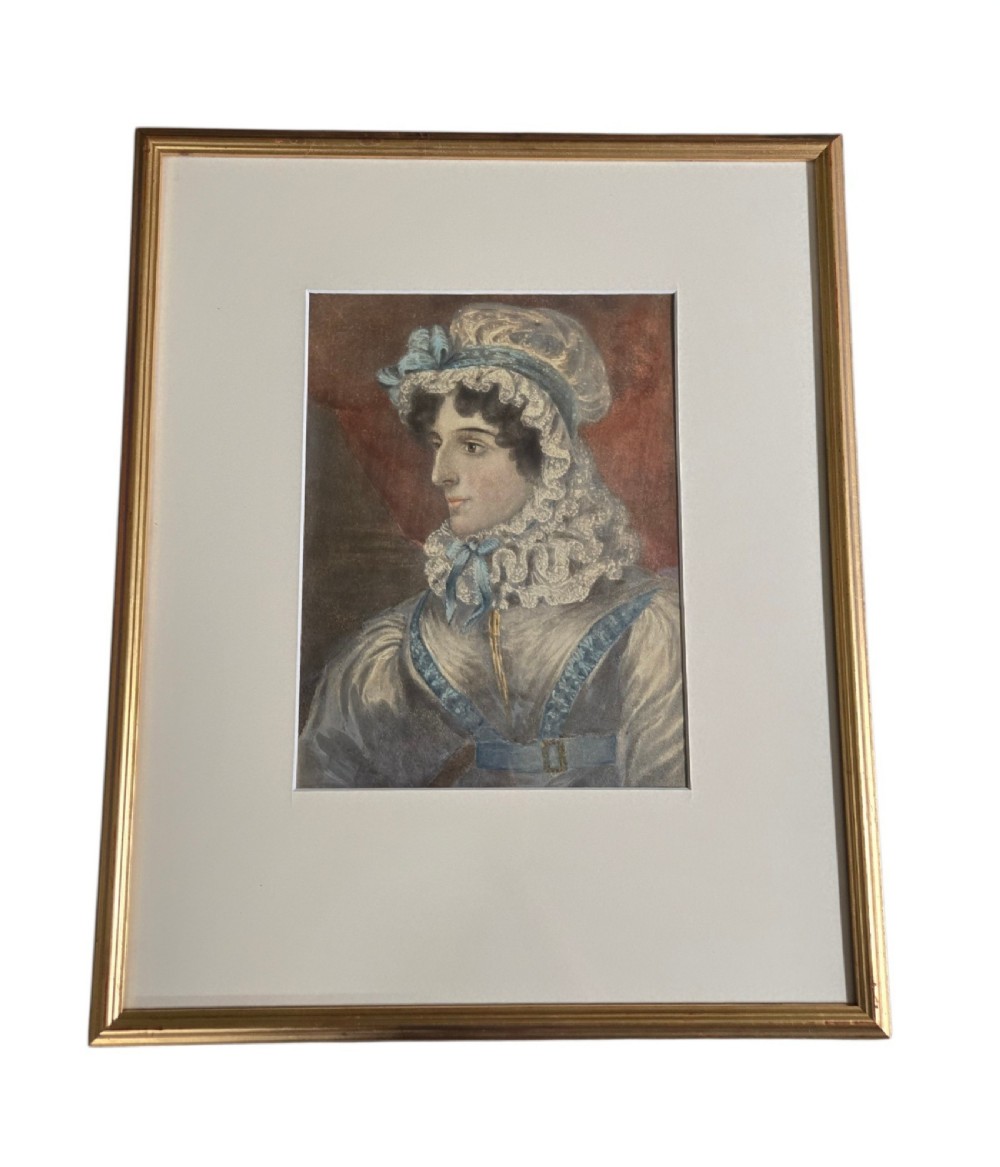 A framed 19th-century watercolour portrait depicting a lady wearing a lace bonnet trimmed with blue ribbons. View IV