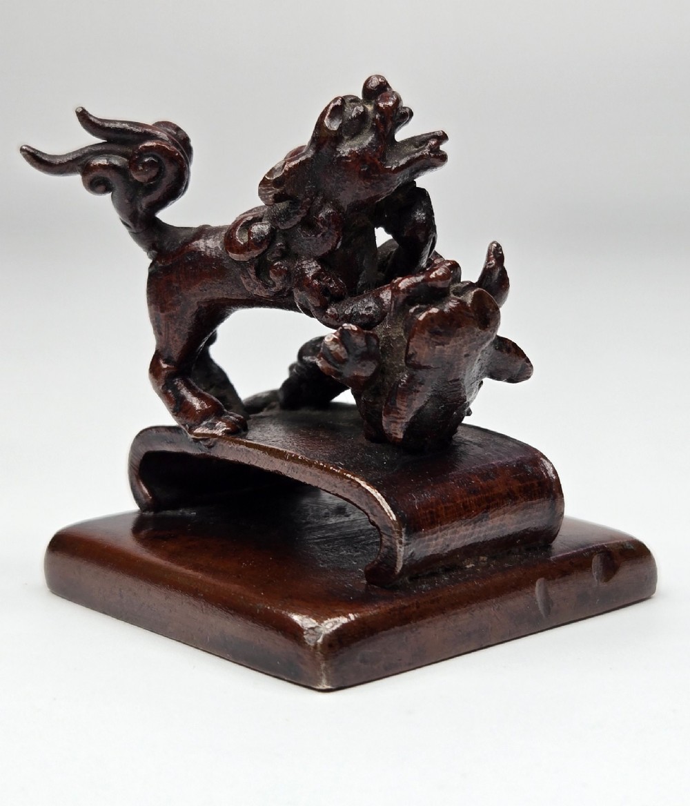 A dark bronze Chinese scholars seal topped with two sculptural wrestling shishi lions resting on an arched platform atop a square base. View II