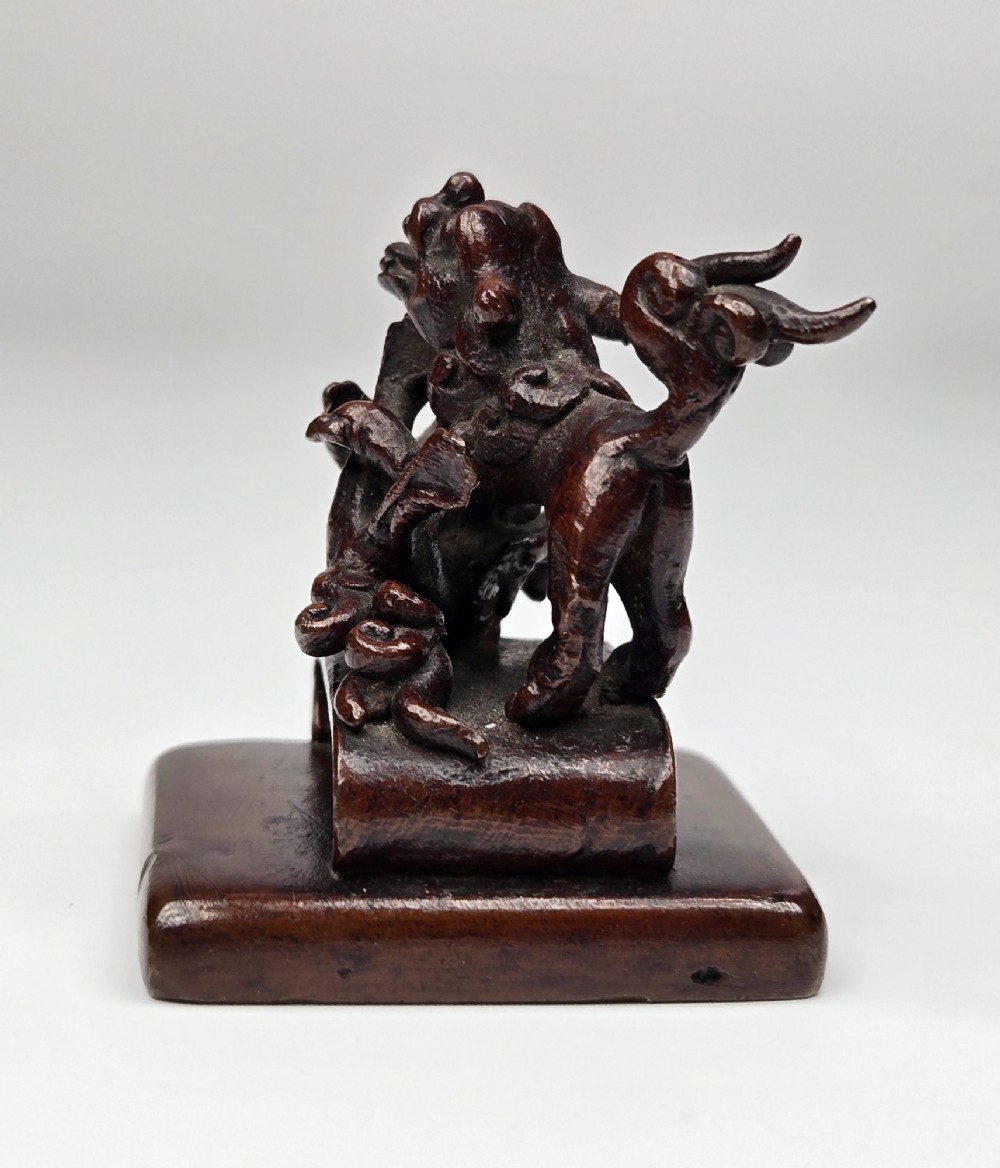A dark bronze Chinese scholars seal topped with two sculptural wrestling shishi lions resting on an arched platform atop a square base. View V