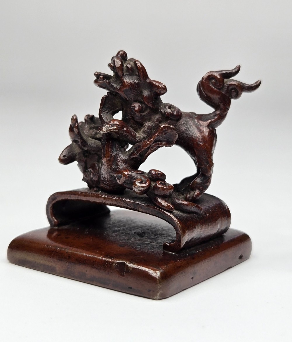 A dark bronze Chinese scholars seal topped with two sculptural wrestling shishi lions resting on an arched platform atop a square base. View VI