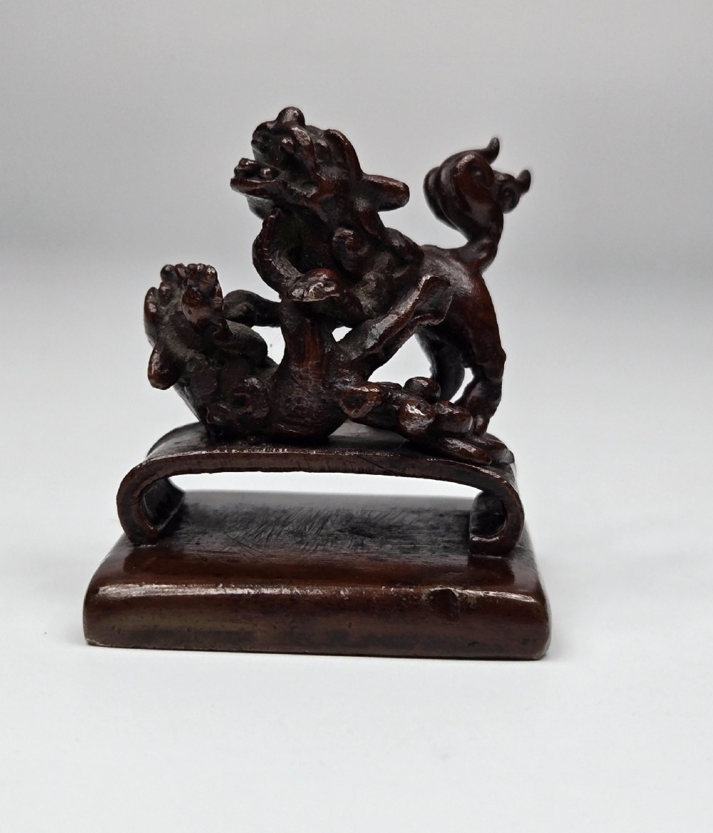 A dark bronze Chinese scholars seal topped with two sculptural wrestling shishi lions resting on an arched platform atop a square base. View VII
