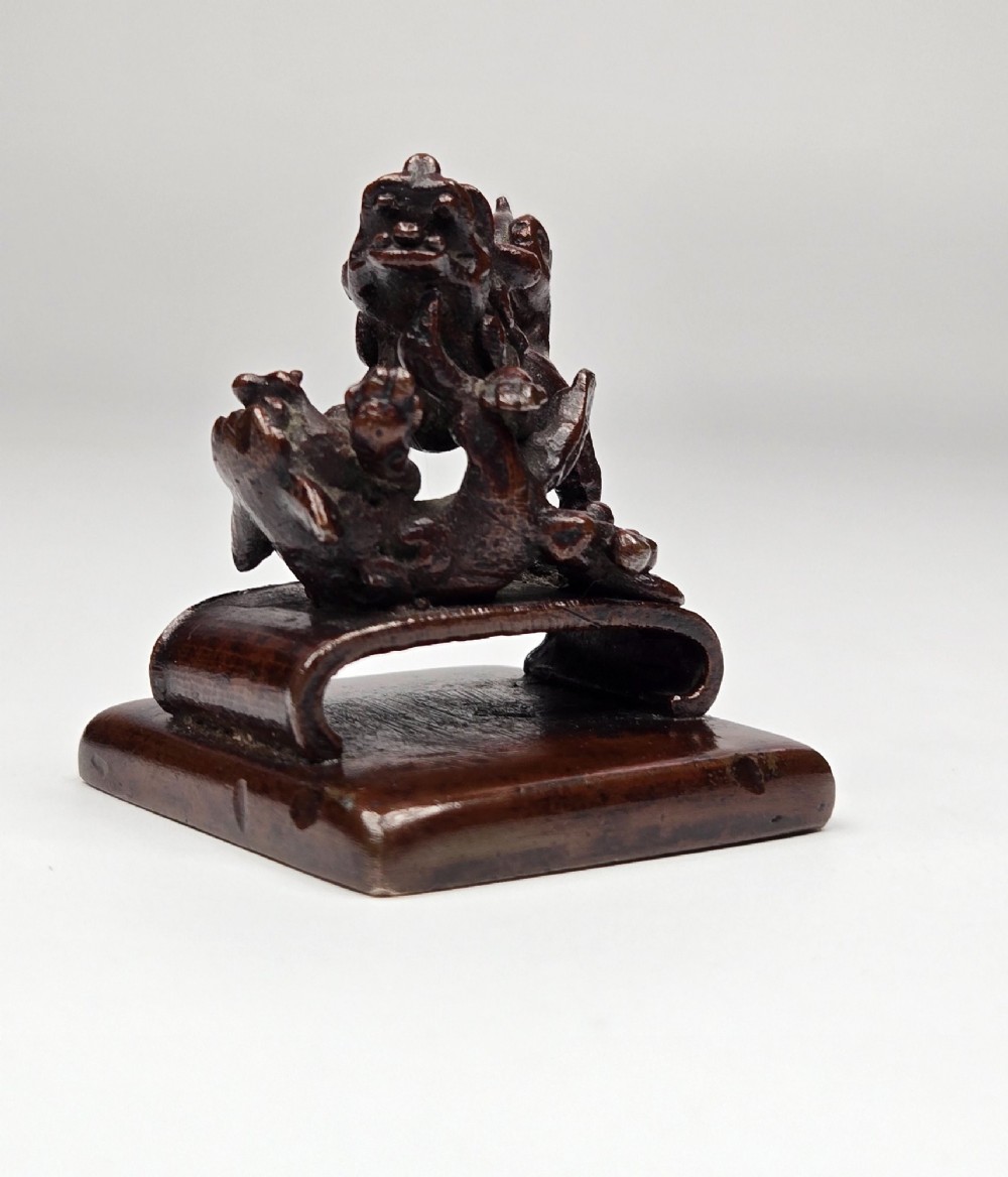 A dark bronze Chinese scholars seal topped with two sculptural wrestling shishi lions resting on an arched platform atop a square base. View VIII