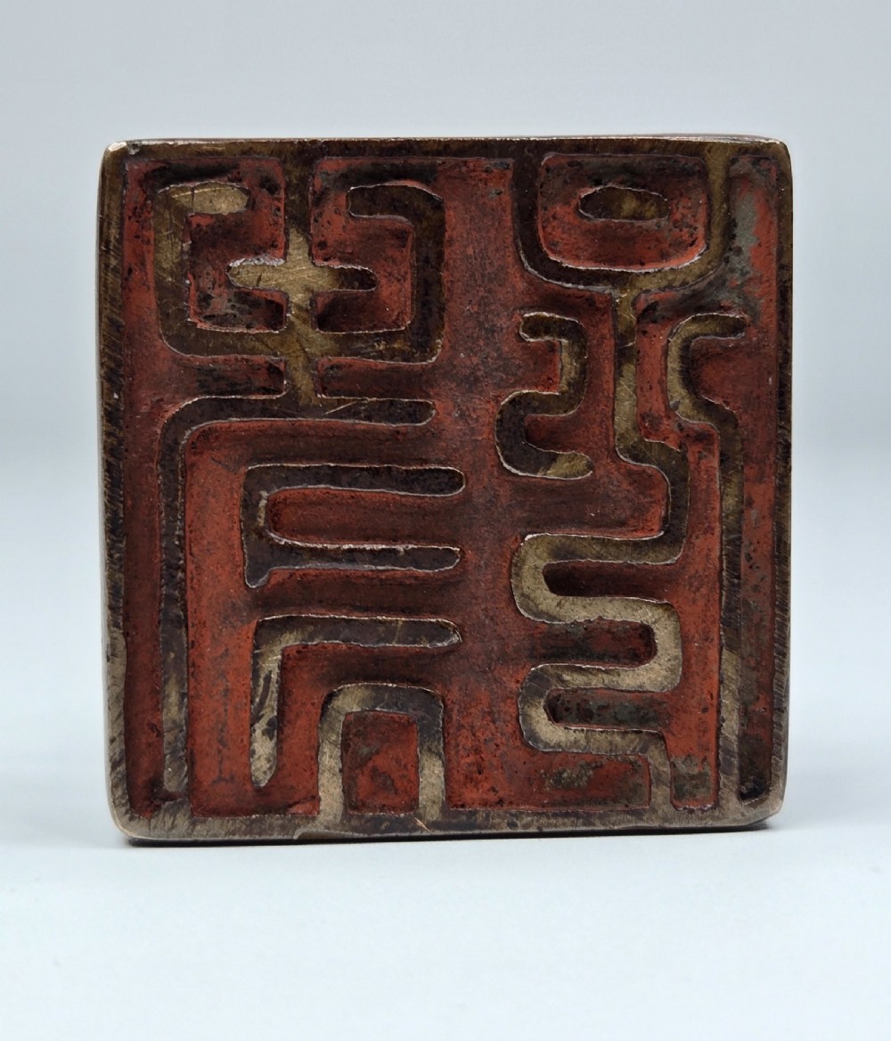 A dark bronze Chinese scholars seal topped with two sculptural wrestling shishi lions resting on an arched platform atop a square base. View X