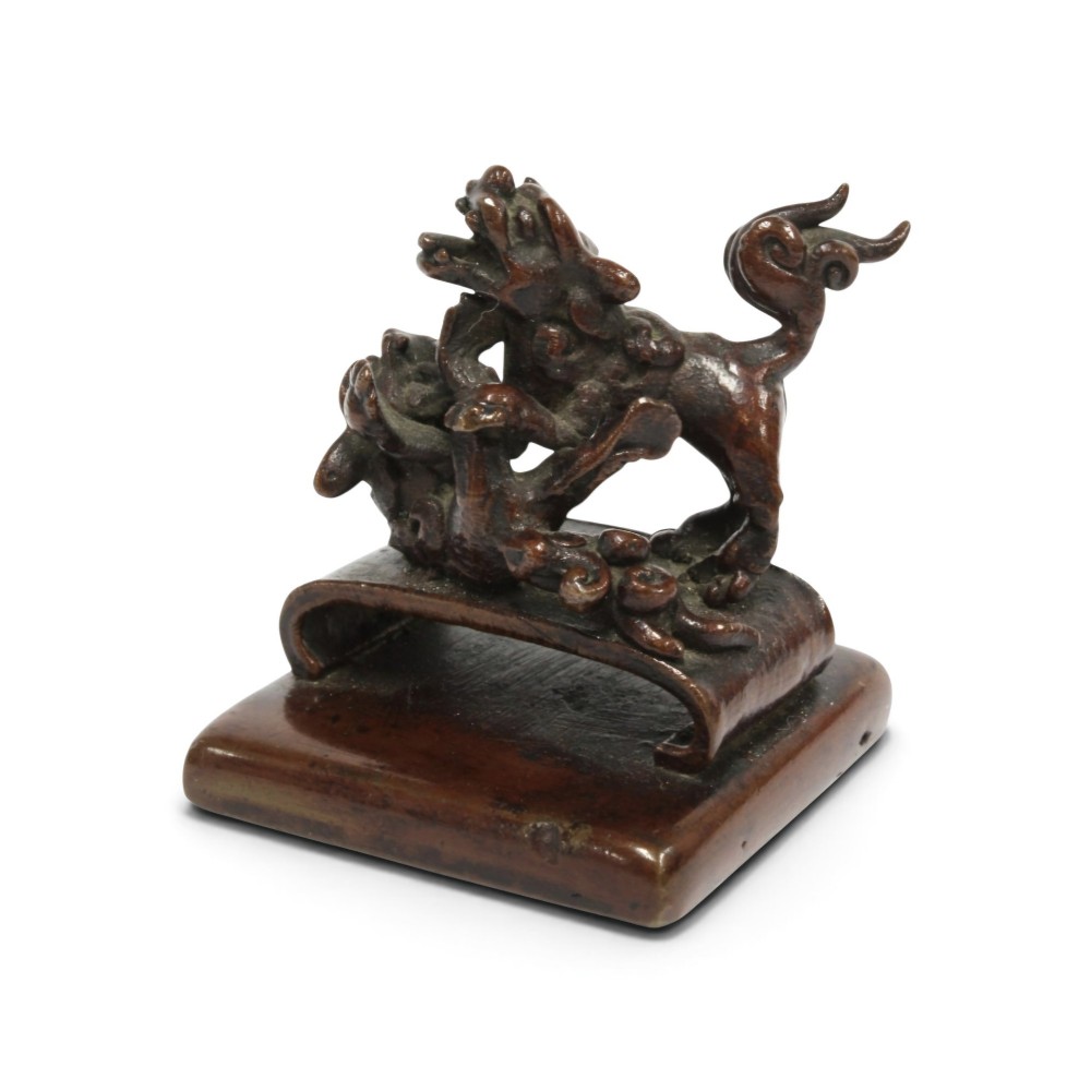 A dark bronze Chinese scholars seal topped with two sculptural wrestling shishi lions resting on an arched platform atop a square base. View XII