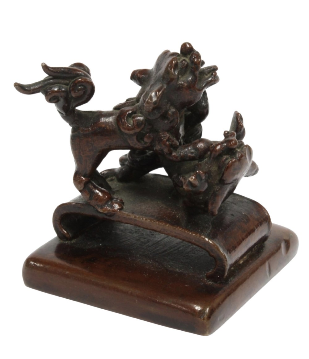A dark bronze Chinese scholars seal topped with two sculptural wrestling shishi lions resting on an arched platform atop a square base. View XIII