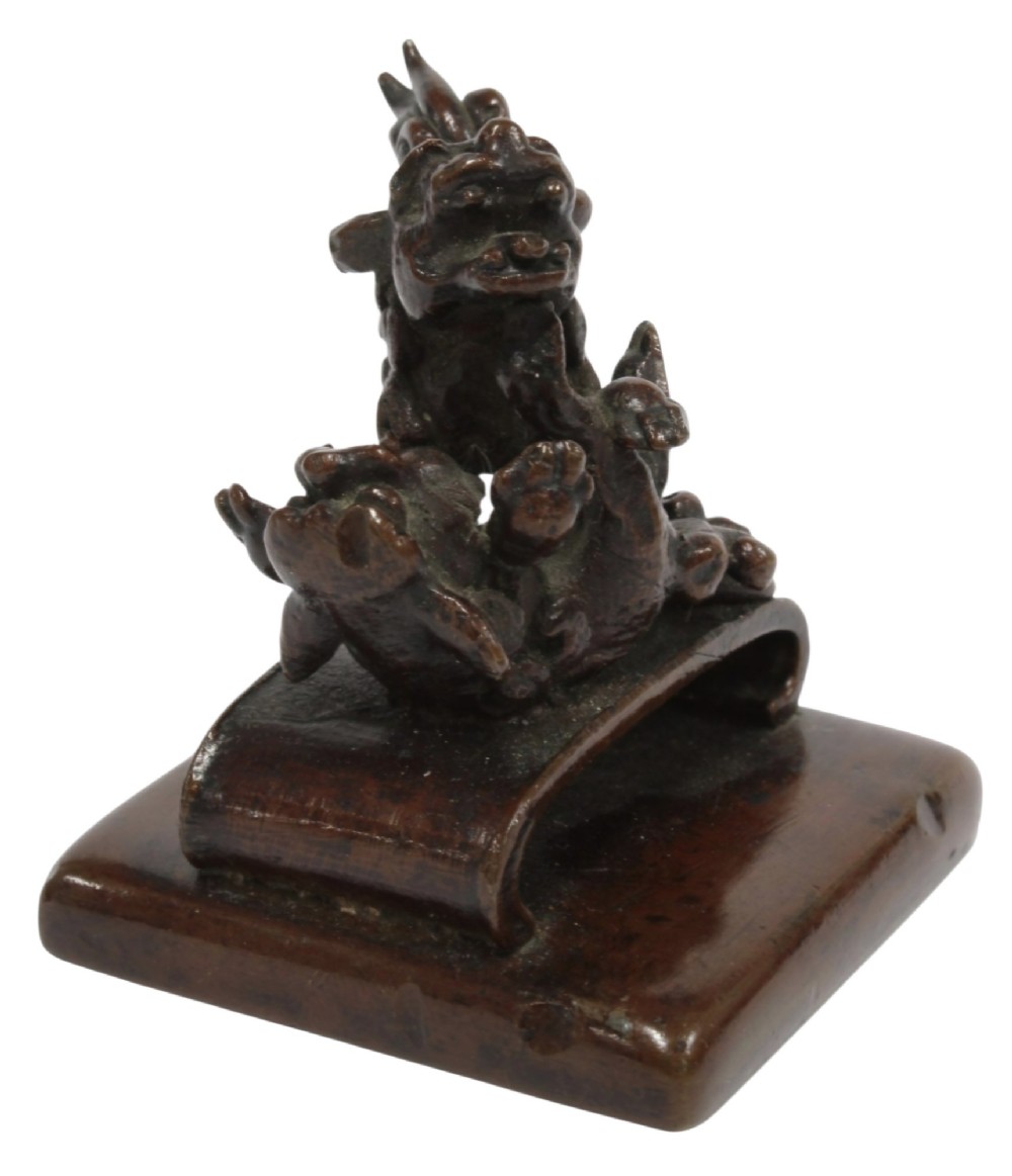 A dark bronze Chinese scholars seal topped with two sculptural wrestling shishi lions resting on an arched platform atop a square base. View XIV