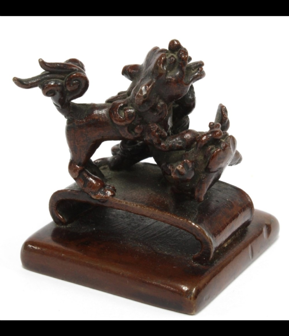 A dark bronze Chinese scholars seal topped with two sculptural wrestling shishi lions resting on an arched platform atop a square base. View XV