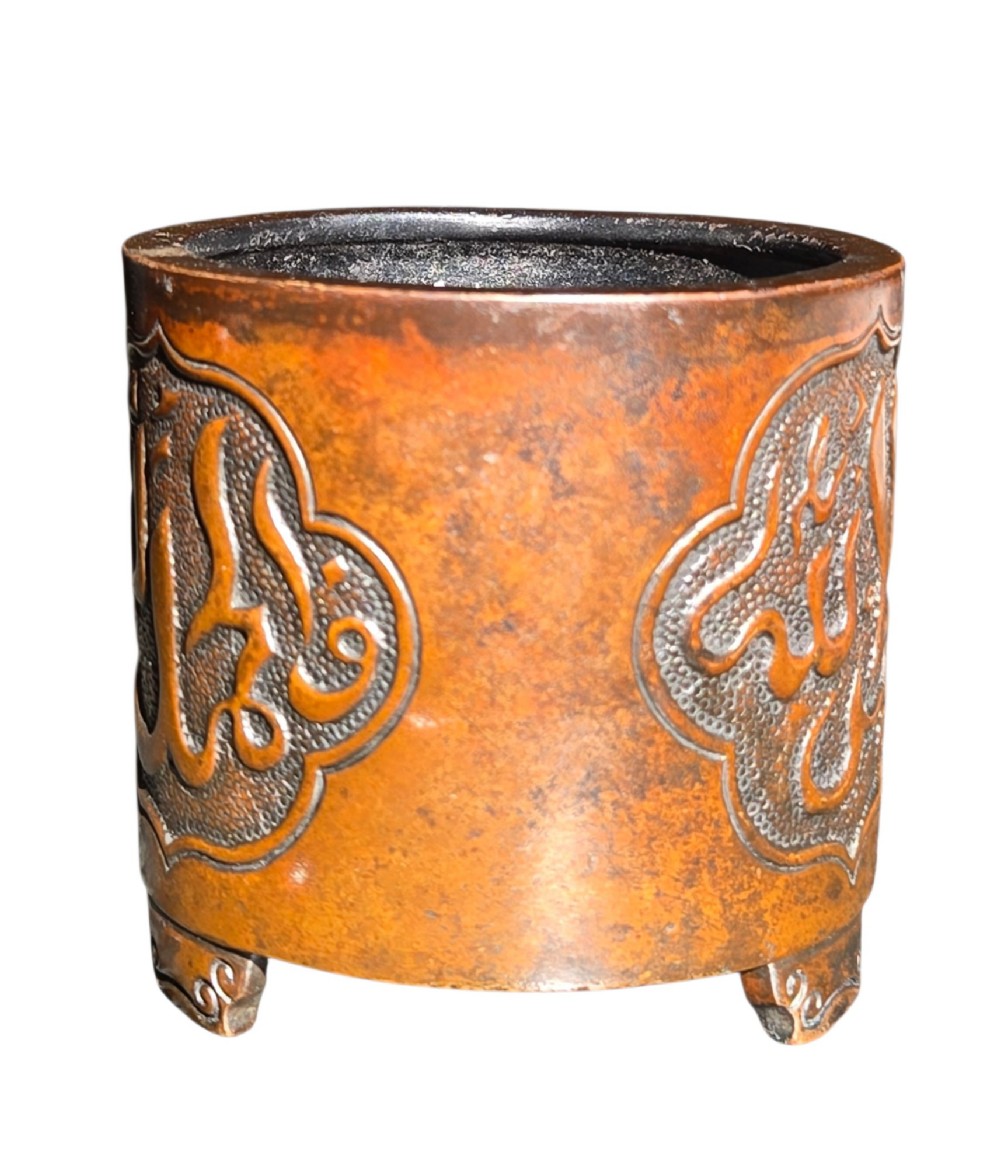 A cylindrical warm brown bronze tripod censer featuring a raised lobed cartouche with Arabic calligraphy set against a textured ground. View III