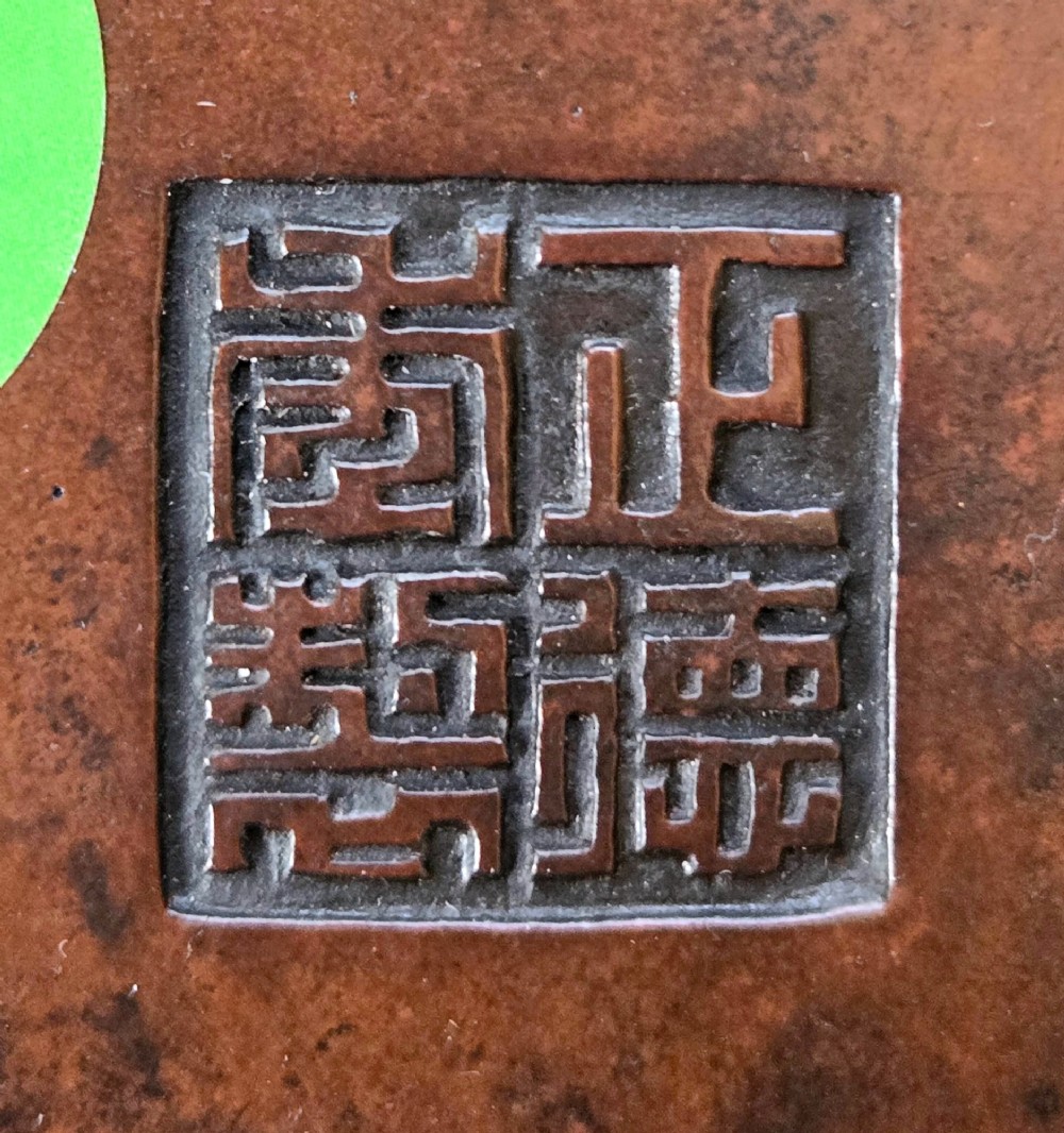 A cylindrical warm brown bronze tripod censer featuring a raised lobed cartouche with Arabic calligraphy set against a textured ground. View XV