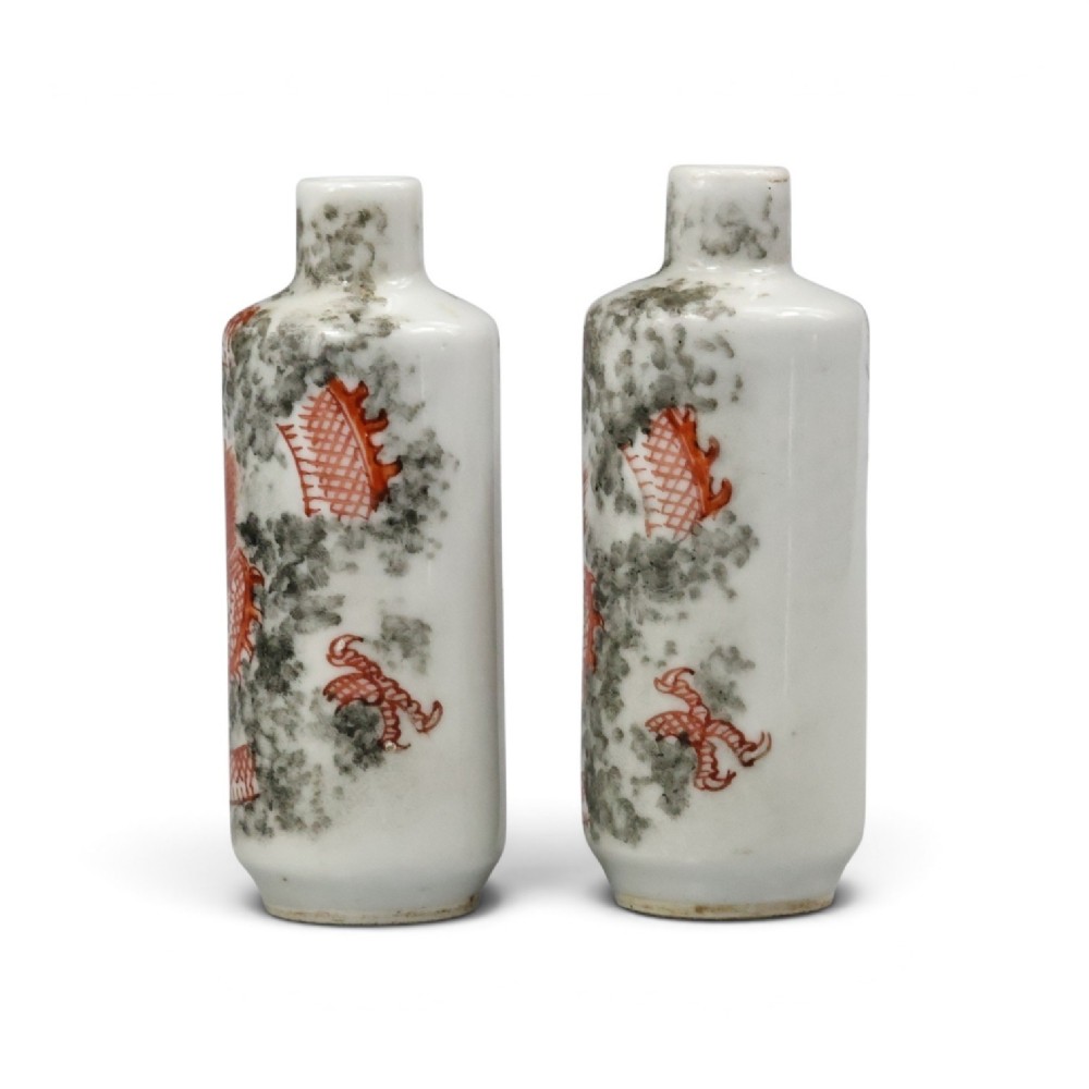 A matched pair of cylindrical off-white Chinese porcelain snuff bottles decorated with detailed iron-red dragons amongst grey clouds. View III