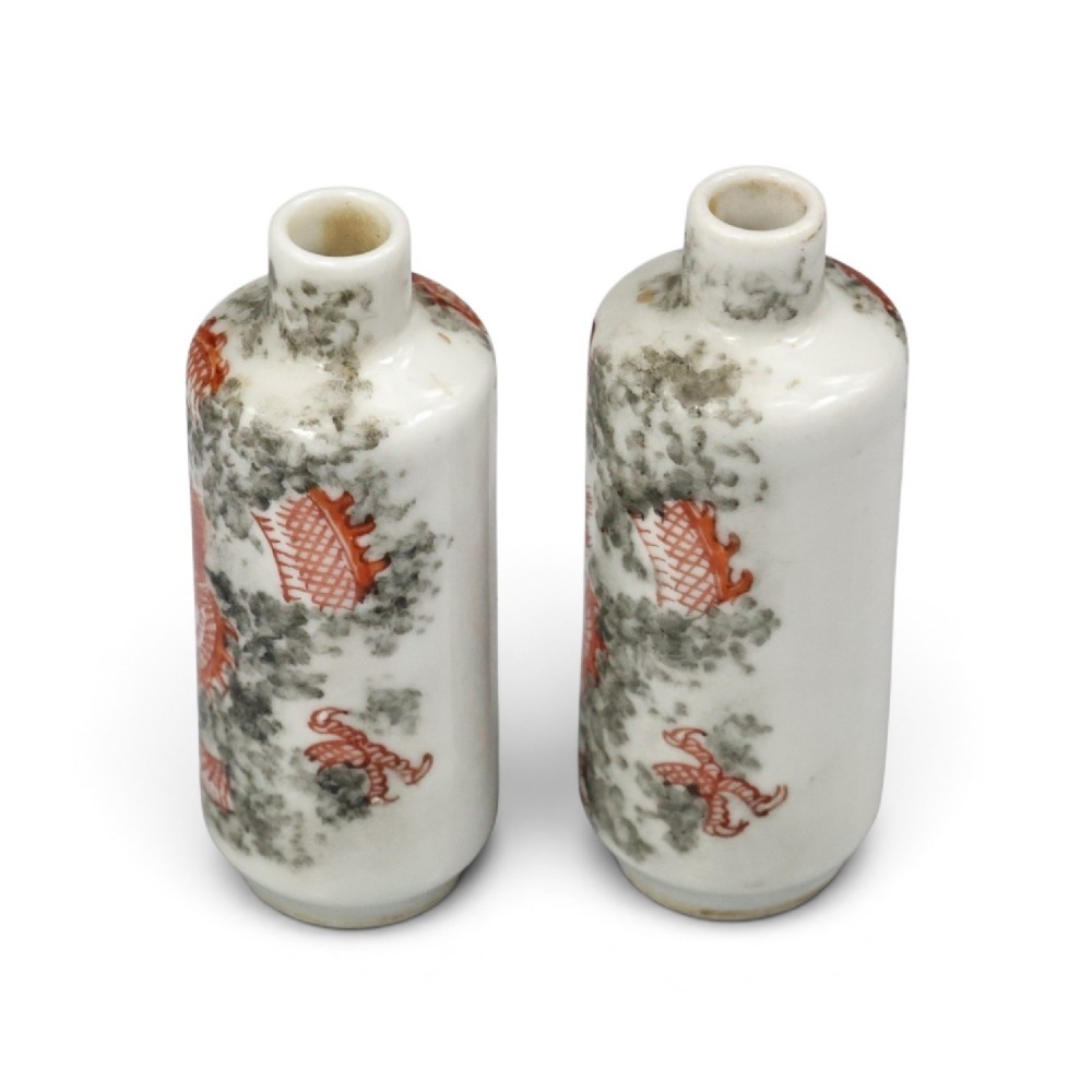 A matched pair of cylindrical off-white Chinese porcelain snuff bottles decorated with detailed iron-red dragons amongst grey clouds. View IV