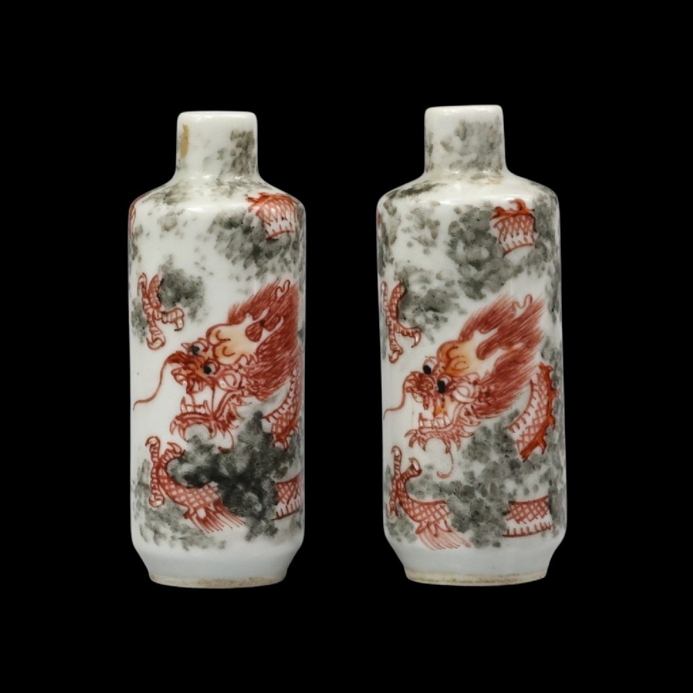 A matched pair of cylindrical off-white Chinese porcelain snuff bottles decorated with detailed iron-red dragons amongst grey clouds. View VI