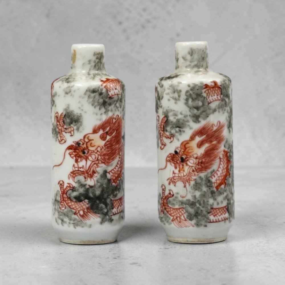 A matched pair of cylindrical off-white Chinese porcelain snuff bottles decorated with detailed iron-red dragons amongst grey clouds. View VII