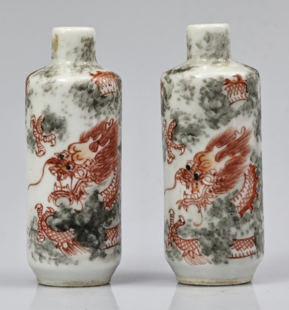 A matched pair of cylindrical off-white Chinese porcelain snuff bottles decorated with detailed iron-red dragons amongst grey clouds. View VIII