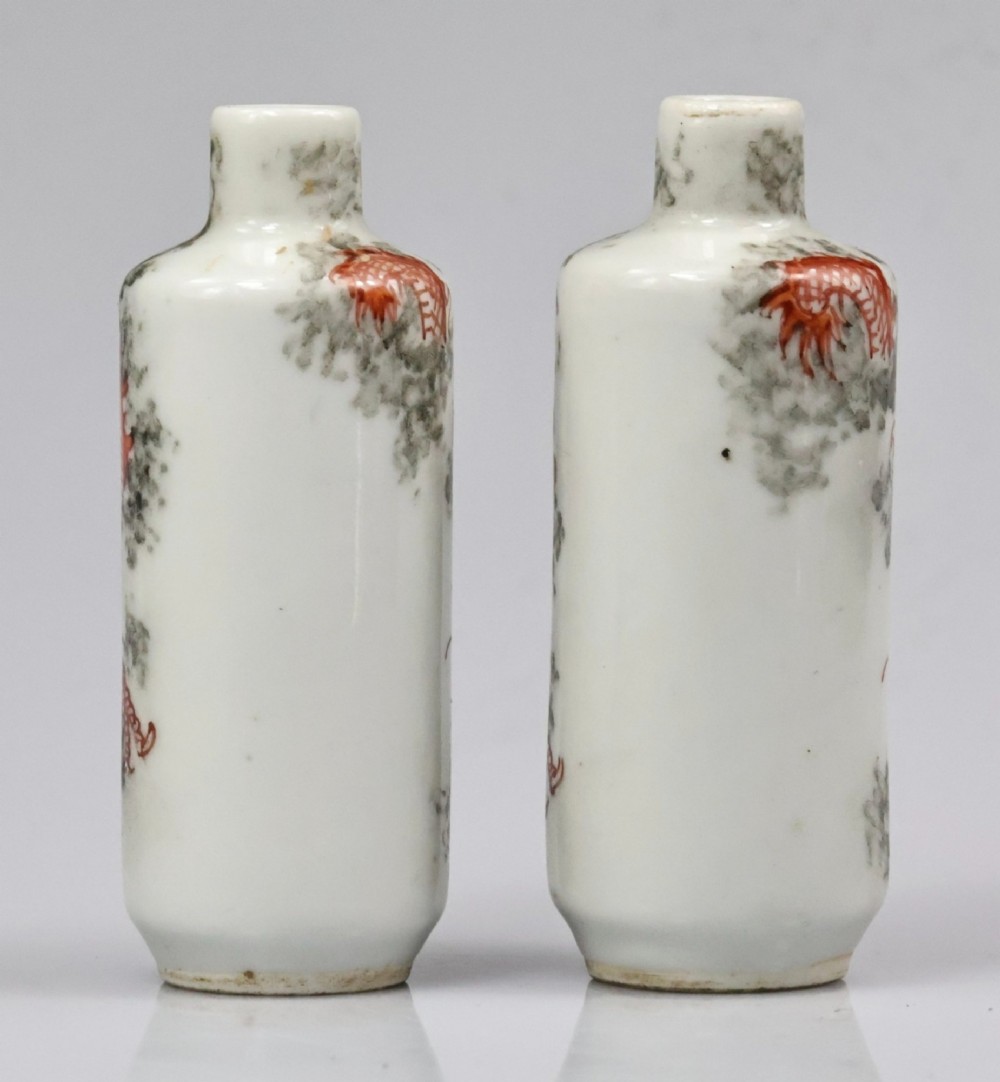 A matched pair of cylindrical off-white Chinese porcelain snuff bottles decorated with detailed iron-red dragons amongst grey clouds. View IX