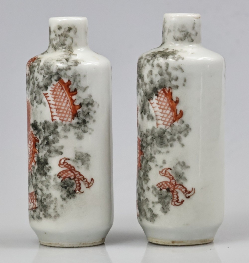 A matched pair of cylindrical off-white Chinese porcelain snuff bottles decorated with detailed iron-red dragons amongst grey clouds. View X