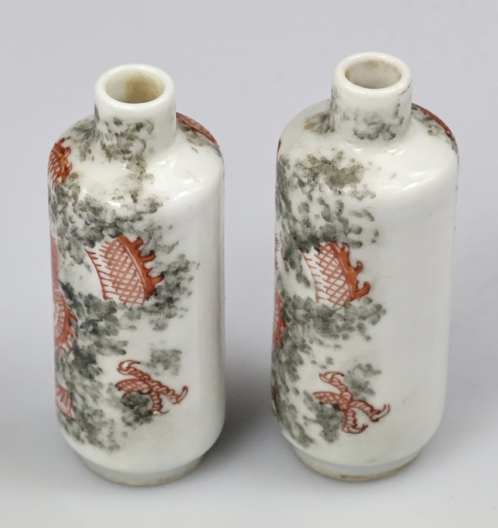A matched pair of cylindrical off-white Chinese porcelain snuff bottles decorated with detailed iron-red dragons amongst grey clouds. View XI