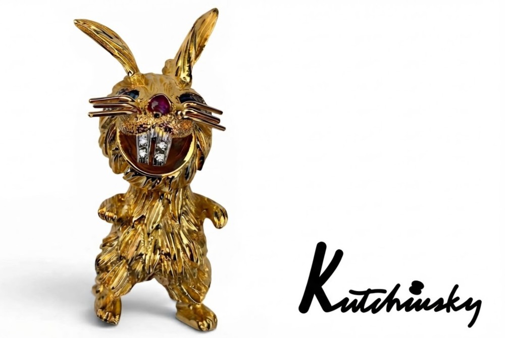 An 18ct yellow gold rabbit brooch showcasing textured fur detailing, a ruby nose, diamond-set teeth, and sapphire eyes.
