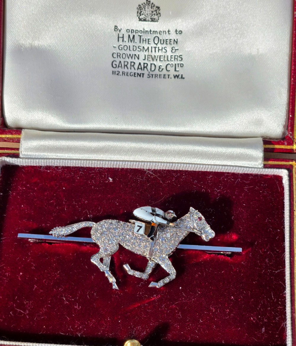 A platinum-topped 18ct gold brooch shaped as a galloping racehorse set with diamonds, ridden by a jockey in black and white enamel silks with number seven. View III