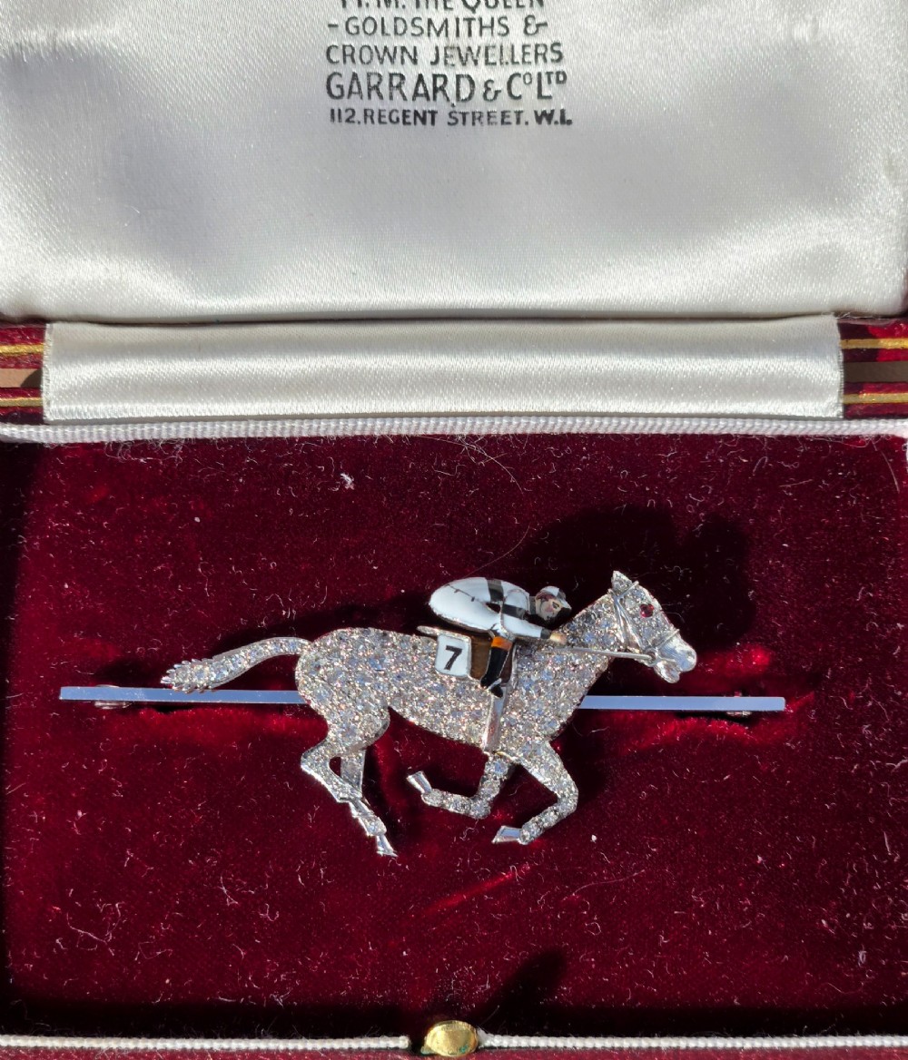 A platinum-topped 18ct gold brooch shaped as a galloping racehorse set with diamonds, ridden by a jockey in black and white enamel silks with number seven. View IV
